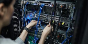 Data center technician adjusting network cables on server racks.